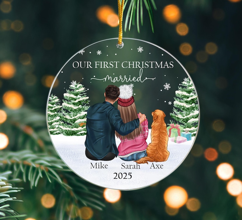 May include: A clear, round Christmas ornament with the text "OUR FIRST CHRISTMAS married" and the names "Mike", "Sarah", and "Axe" with the year "2025". The ornament features a couple, a dog, and Christmas trees.