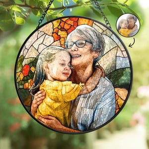May include: A stained glass suncatcher featuring a colorful mosaic design with a photo of a woman and a child embracing. The photo is framed in a circle and is surrounded by a colorful mosaic design.