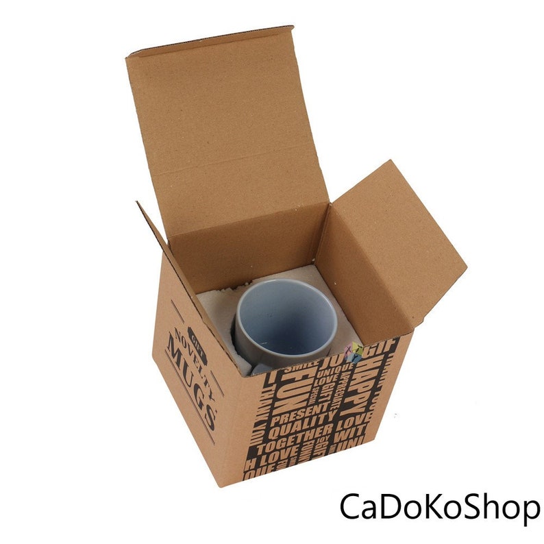 K&ouml;nnte beinhalten: Ein brauner Karton mit der Aufschrift "Novelty Mugs" auf der Seite. Der Karton ist ge&ouml;ffnet und enth&auml;lt eine hellblaue Keramiktasse. Der Karton ist mit wei&szlig;en Verpackungschips gef&uuml;llt.