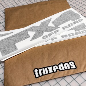 May include: Three gray vinyl decals with the text "FX4 OFF ROAD" on a brown paper envelope with the text "TRUXPEDOS" on the bottom.