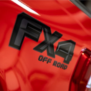 May include: A red truck with a black "FX4 OFF ROAD" emblem on the side.