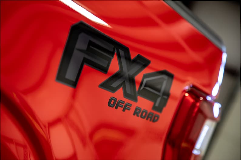 May include: A red truck with a black "FX4 OFF ROAD" emblem on the side.