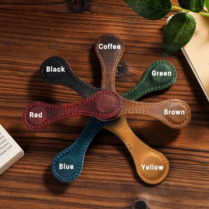 May include: Seven leather bookmarks in different colors, including red, black, coffee, green, blue, yellow, and brown. Each bookmark has a small circle at the top with the color name written in white.