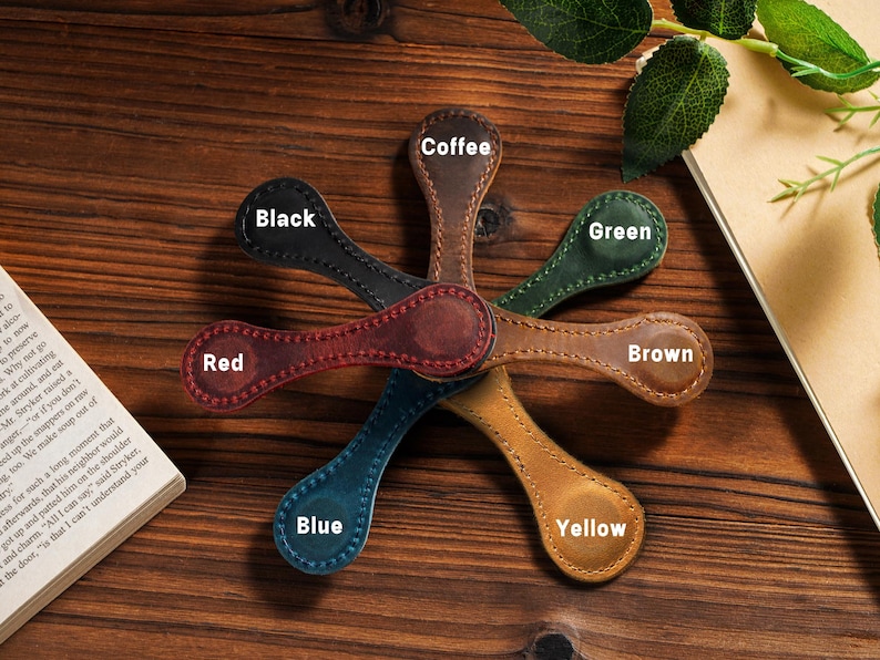 May include: Seven leather bookmarks in different colors, including red, black, coffee, green, blue, yellow, and brown. Each bookmark has a small circle at the top with the color name written in white.