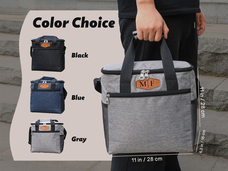 Puede incluir: Una bolsa de almuerzo aislada gris con un parche de cuero marr&oacute;n que dice "MF". La bolsa tiene un cierre de cremallera y un asa negra. La bolsa mide 28 cm de ancho y 16 cm de alto. La bolsa est&aacute; disponible en negro, azul y gris.