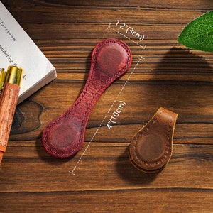 May include: Two leather book markers. One is red and 4 inches long and 1.2 inches wide. The other is brown and smaller. Both have a stitched edge.