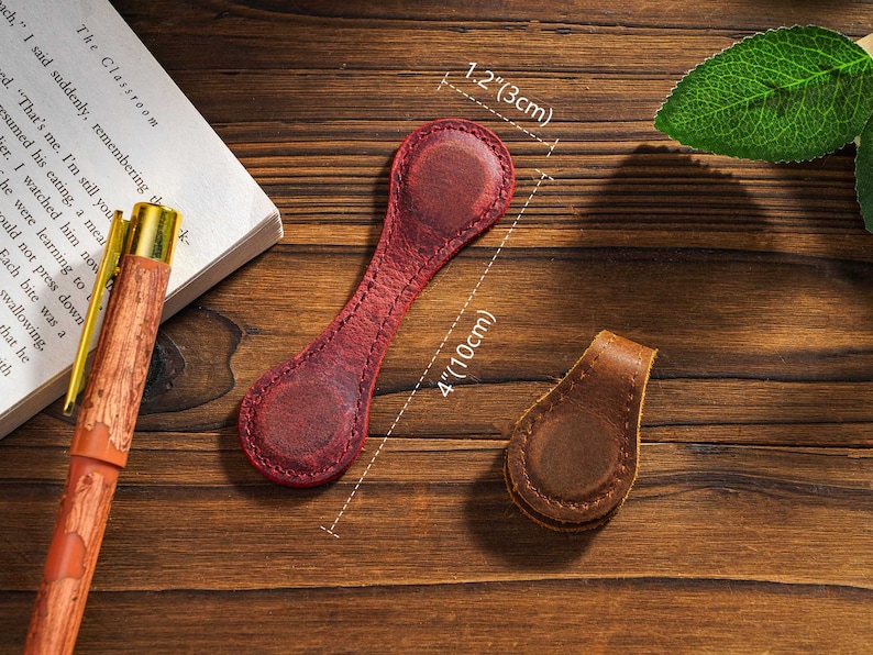 May include: Two leather book markers. One is red and 4 inches long and 1.2 inches wide. The other is brown and smaller. Both have a stitched edge.