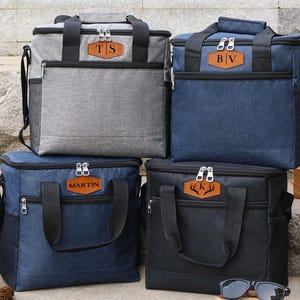 Puede incluir: Cuatro bolsas isot&eacute;rmicas personalizadas con diferentes colores e iniciales. Las bolsas tienen cierre de cremallera y asa superior. Las iniciales est&aacute;n en un parche de cuero marr&oacute;n.