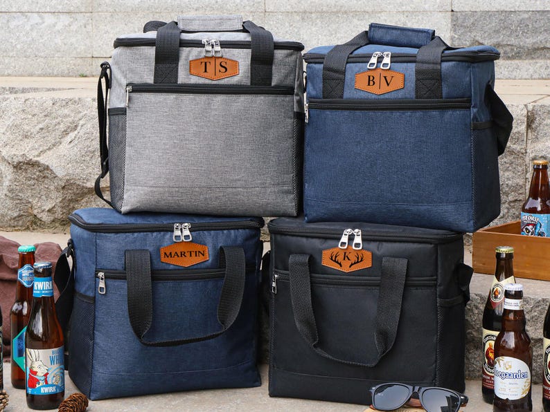 Puede incluir: Cuatro bolsas isot&eacute;rmicas personalizadas con diferentes colores e iniciales. Las bolsas tienen cierre de cremallera y asa superior. Las iniciales est&aacute;n en un parche de cuero marr&oacute;n.