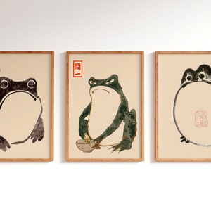 Könnte beinhalten: Drei gerahmte Drucke von japanischen Froschillustrationen. Der erste Frosch ist schwarzweiß, der zweite grünweiß und der dritte ist eine schwarzweiße Umrandung eines Frosches.