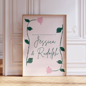 May include: A pink and green wedding sign with the text "Welcome to the wedding of Jessica & Rudolph" surrounded by stylised floral vines.