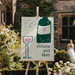 Könnte beinhalten: Ein weißes Hochzeitsschild mit grünen und rosa Illustrationen einer Weinflasche und eines Weinglases. Das Schild lautet "31 06 2025 Willkommen zur Hochzeit von Victoria und Matt".