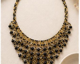 May include: A bib necklace crafted from a complex lattice of small black and gold beads. The design features a wide, triangular-shaped collar with larger black beads integrated into the woven pattern, finished with a simple clasp closure at the top.