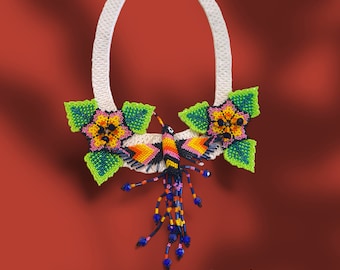 May include: A white beaded necklace with a hummingbird and flower design. The hummingbird is made of colorful beads and has a long tail. The flowers are yellow, pink, and green.