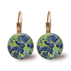 May include: A pair of gold-toned earrings with a round, blue and green glass cabochon featuring a painting of irises.
