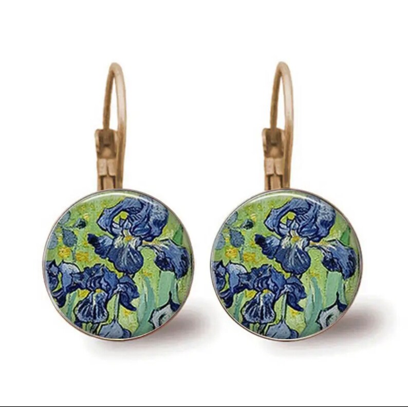 May include: A pair of gold-toned earrings with a round, blue and green glass cabochon featuring a painting of irises.