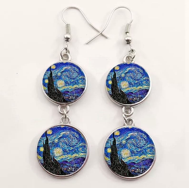 May include: A pair of silver dangle earrings with two round glass charms featuring a reproduction of Vincent van Gogh's "The Starry Night" painting.