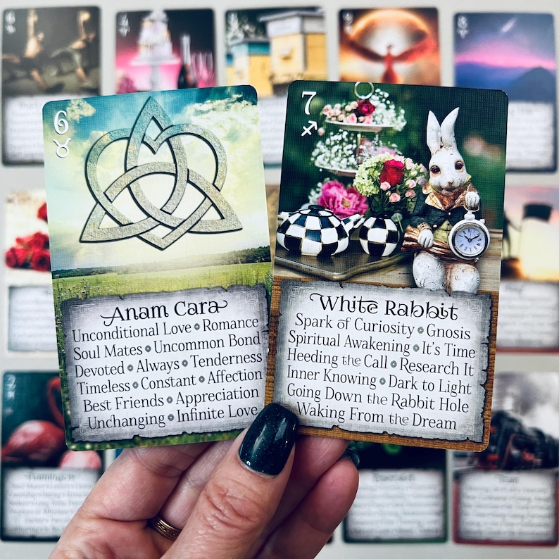 May include: Two tarot cards, one with a Celtic knot design and the words "Anam Cara" and the other with a white rabbit holding a pocket watch and the words "White Rabbit".