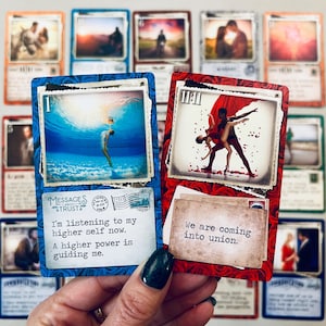 May include: Two oracle cards with blue and red backgrounds. The blue card has the number 1 and a picture of a woman diving underwater. The text on the card reads "I'm listening to my higher self now. A higher power is guiding me." The red card has the number 11:11 and a picture of a couple dancing. The text on the card reads "We are coming into union."