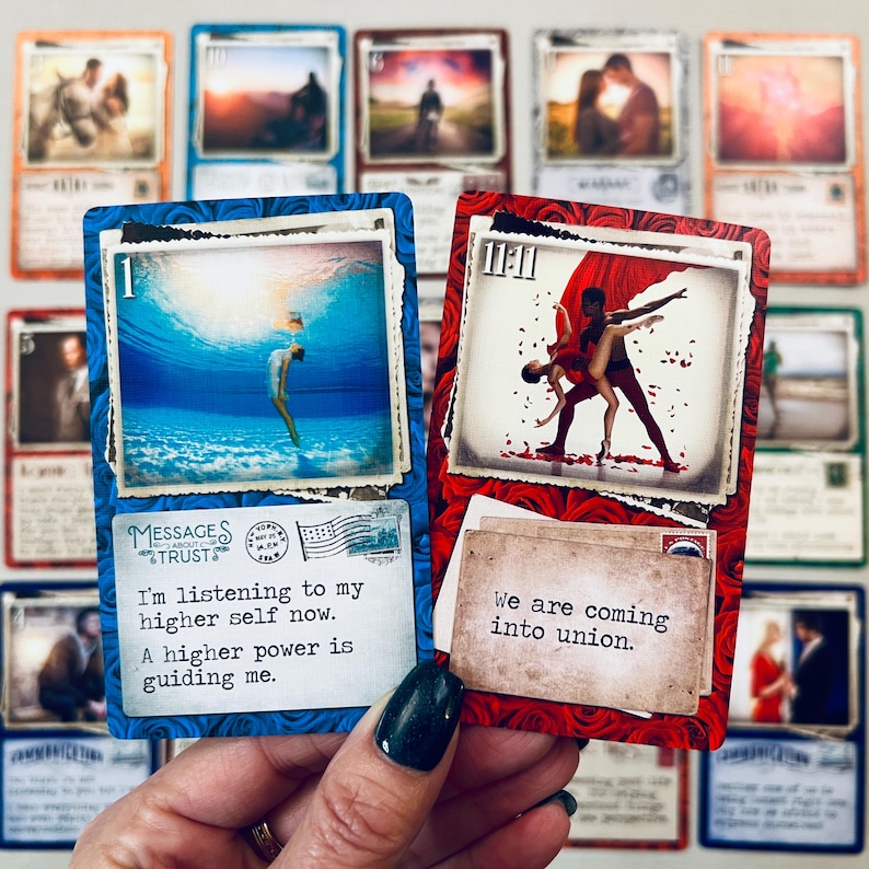May include: Two oracle cards with blue and red backgrounds. The blue card has the number 1 and a picture of a woman diving underwater. The text on the card reads "I'm listening to my higher self now. A higher power is guiding me." The red card has the number 11:11 and a picture of a couple dancing. The text on the card reads "We are coming into union."