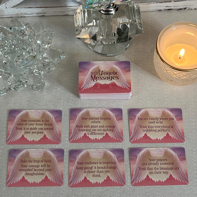 Puede incluir: Un juego de cartas de afirmaci&oacute;n con alas de &aacute;ngel rosa y blancas con mensajes inspiradores. Las cartas presentan un fondo rosa y blanco con un dise&ntilde;o de alas de &aacute;ngel blancas. El texto en las cartas incluye mensajes como "Tu intuici&oacute;n es la voz de tu Ser Interior" y "Tu viaje inspira a los dem&aacute;s."