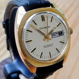 May include: A vintage gold-toned Cortébert automatic wristwatch with a black leather band. The watch face is white with black markers and hands, and the date is displayed as MIT 15. The watch is labeled "AUTOMATIC 25 JEWELS".