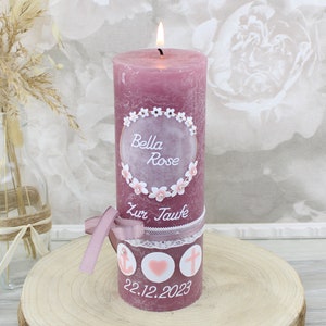 Könnte beinhalten: Eine rosa Taufkerze mit weißen Blüten und einem weißen Kreis mit dem Text "Bella Rose Zur Taufe" und dem Datum "22.12.2023".