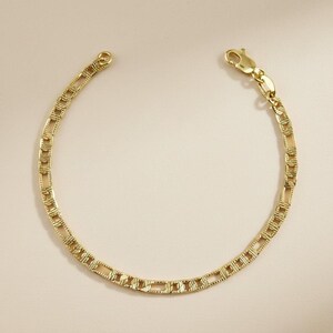 May include: A gold bracelet featuring a rectangular link chain design. The bracelet has a lobster clasp and a small loop. The links have a textured pattern. The bracelet is displayed against a neutral background.