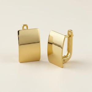 May include: A pair of polished gold-tone hoop earrings featuring a smooth, rectangular front panel with a curved design. The earrings have a hinged closure mechanism that secures the piece, showcasing a reflective metallic finish throughout.