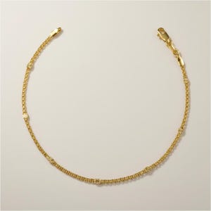 Peut inclure: Un bracelet délicat de couleur or avec un motif de chaîne. Le bracelet comporte de petits accents décoratifs en forme de fleur. Le fermoir et la chaîne sont visibles sur un fond neutre. Ce bijou convient au quotidien.
