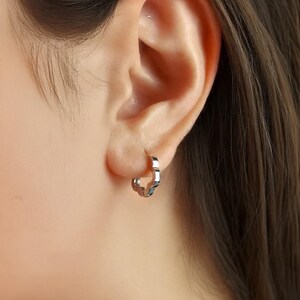 These platinum hoop earrings showcase a modern floral-inspired design, blending soft petal-like curves with a sleek geometric edge. Crafted in premium platinum, they radiate understated elegance while remaining durable for everyday wear. Lightweight and versatile, they effortlessly complement both casual and formal outfits. A refined expression of timeless style, these earrings make a graceful addition to any jewellery collection.