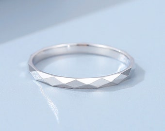 May include: A silver ring with a geometric, faceted design. The ring is thin and delicate.