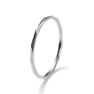 May include: A silver ring with a faceted, geometric design. The ring is simple and modern.