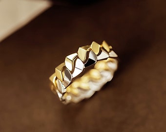 Può includere: Un anello in oro bicolore con un design unico e intrecciato. L'anello è realizzato in oro giallo e bianco, creando un contrasto sorprendente.