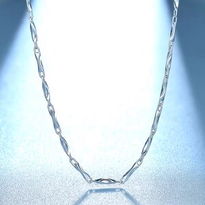 May include: A silver chain necklace with a unique, wavy link design. The chain is made of metal and has a polished finish.