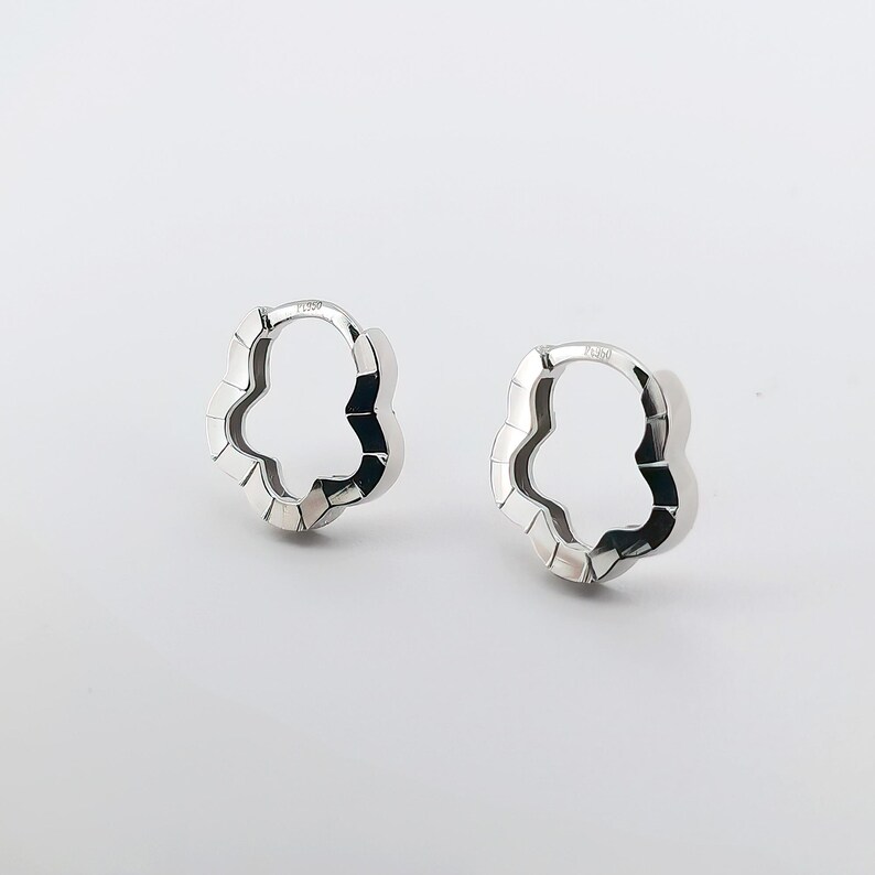 These platinum hoop earrings showcase a modern floral-inspired design, blending soft petal-like curves with a sleek geometric edge. Crafted in premium platinum, they radiate understated elegance while remaining durable for everyday wear. Lightweight and versatile, they effortlessly complement both casual and formal outfits. A refined expression of timeless style, these earrings make a graceful addition to any jewellery collection.