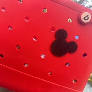 May include: Red plastic tote bag with a black Mickey Mouse silhouette and a white button with the number 6 on it.