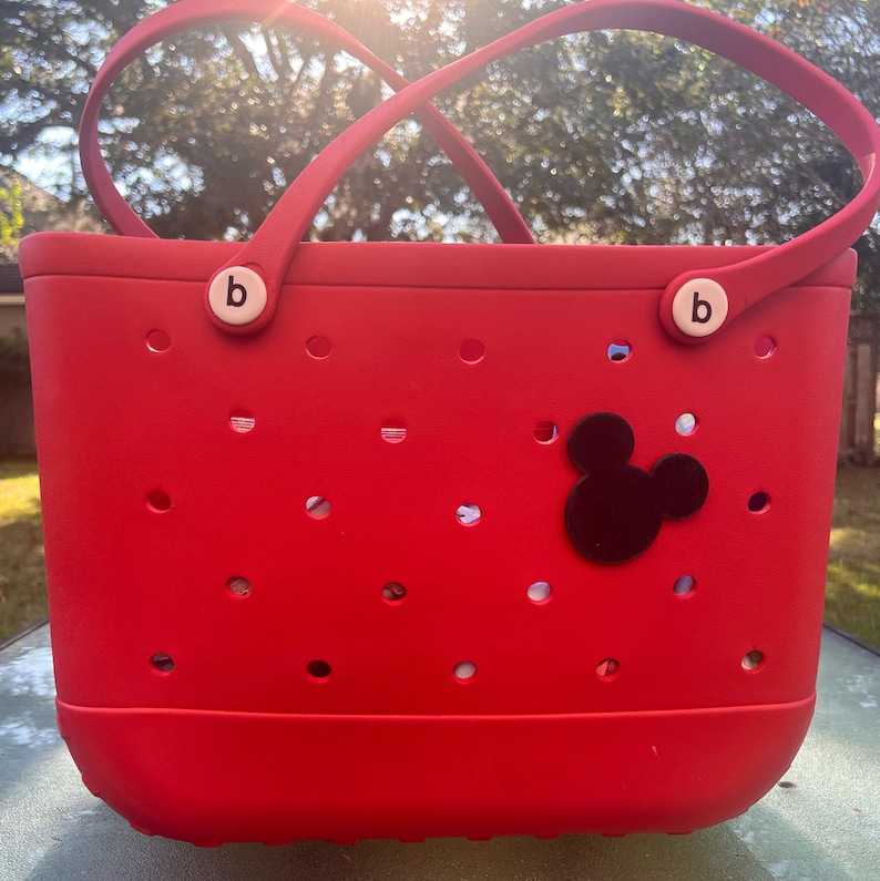 May include: Red tote bag with a black Mickey Mouse head design. The bag has a white "b" on each handle.