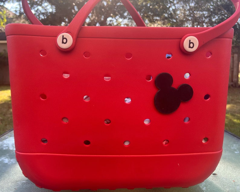 May include: Red tote bag with black Mickey Mouse ears and white "b" buttons on the handles.