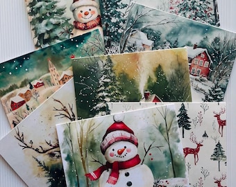 May include: A set of eight watercolor Christmas cards featuring winter scenes with snowmen, deer, and houses. The cards are printed on white cardstock and have a matte finish.
