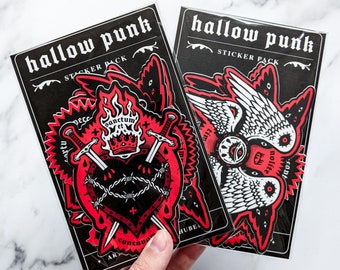 May include: Two sticker packs with the text "hallow punk" and "sticker pack". The left pack features a red heart with barbed wire and two swords, with the text "Sanctum et" above the heart. The right pack features a pair of white wings with the text "Nolite" and "Cant" on the wings.
