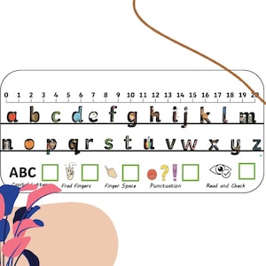 May include: A white rectangular educational desk strip featuring the alphabet from a to z, with each letter illustrated by a small graphic. A number line from 0 to 20 runs along the top. Below, icons represent ABC, Fred Fingers, Finger Space, Punctuation, and Read and Check with corresponding empty green boxes.