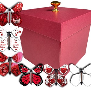May include: A red gift box with a gold knob on the lid. The box is surrounded by eight butterfly pop-up cards with various Valentine's Day themed designs, including hearts, roses, and the text "Happy Valentine's", "More Today Than Yesterday", "But Less Than Tomorrow", and "I Love You".