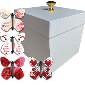 May include: White gift box with a gold knob on the lid. The box is open and there are five pop-up butterfly cards inside. The butterflies have different designs, including roses, hearts, and the words "To Mom With Love", "More Today Than Yesterday", "But Less Than Tomorrow", and "I Love You".