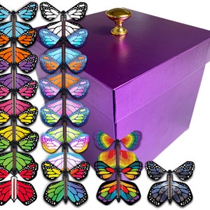 May include: A purple gift box with a gold knob on the lid. The box is surrounded by 18 colorful butterfly toys with flapping wings.