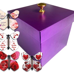 May include: A purple gift box with a gold knob on the lid. The box is surrounded by five butterfly-shaped cards with different designs and messages, including "To Mom With Love", "More Today Than Yesterday", "I Love You", and "Bit Less Than Tomorrow".