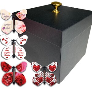 May include: A black gift box with a gold knob on top. Several butterfly-shaped cards with various designs and messages, including "To Mom," "With Love," and "I Love You," are displayed in front of the box.