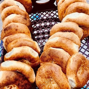 May include: A close-up of a brown wicker basket filled with freshly baked bread rolls. The rolls are golden brown and have a slightly crispy exterior.