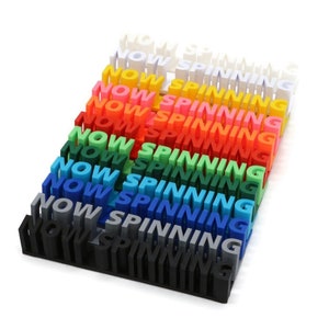 May include: A rainbow-coloured stack of 3D printed words that spell out "NOW SPINNING".
