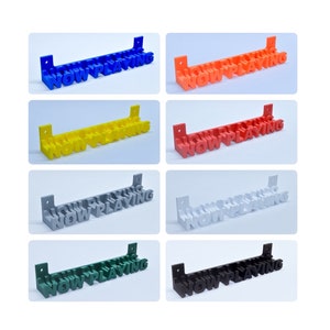 Op de afbeelding: Acht verschillende gekleurde wandborden met de tekst "NOW PLAYING" in 3D-letters. De borden zijn gemaakt van plastic en zijn verkrijgbaar in blauw, oranje, geel, rood, grijs, wit, groen en zwart.